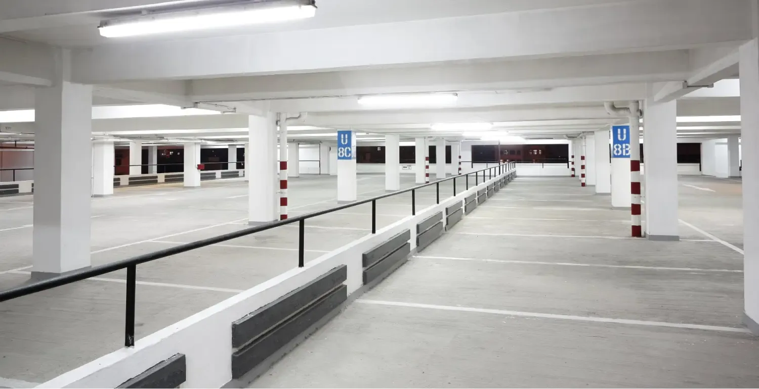 Leere, ausgeleuchtete Tiefgarage mit sauberen Bodenflächen und Stellplatzmarkierungen