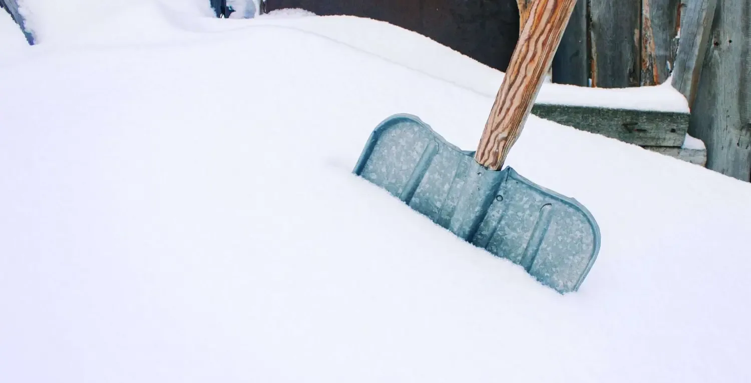 Schneeschaufel in frisch gefallenem Schnee auf einer geräumten Fläche